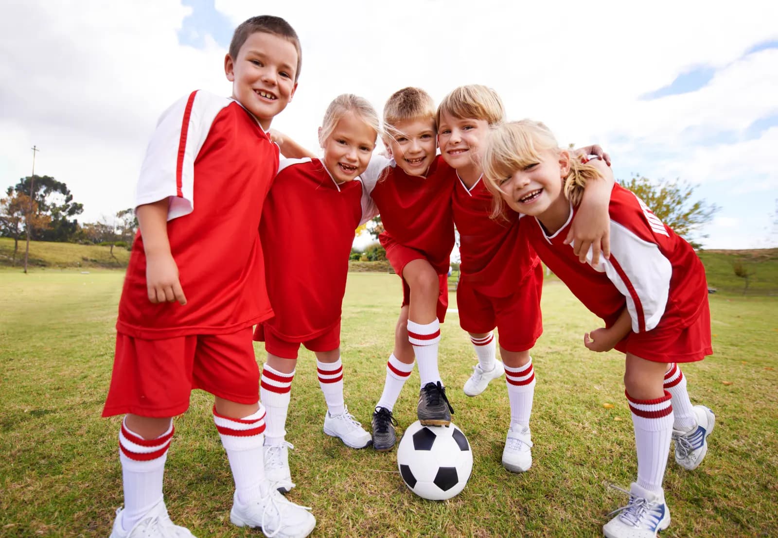 Kinderteam in roten Trikots jubelt auf dem Platz