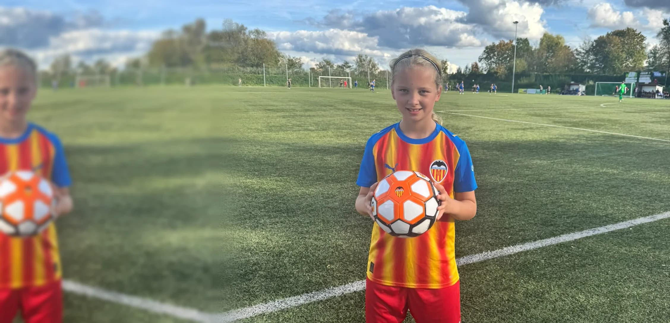 Junge Spielerin im Trikot des Valencia CF hält den Ball mit beiden Händen auf dem Kunstrasenplatz